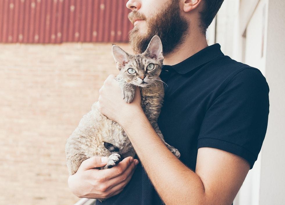 Beared man in black polo holding cat